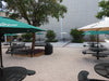Black Wabash Valley Signature Round Pedestal Picnic Tables with Diamond tops and patio umbrellas in a campus courtyard, round outdoor metal table