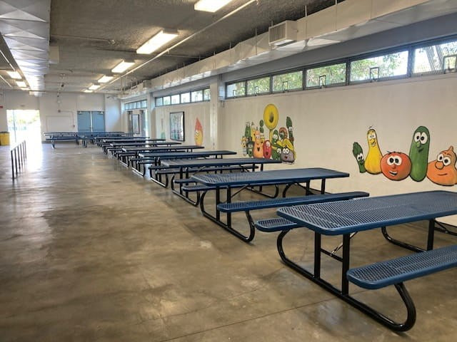 Black & Blue Wabash Valley Signature Portable Picnic Tables lined up indoors in a school cafeteria, lunch tables for schools