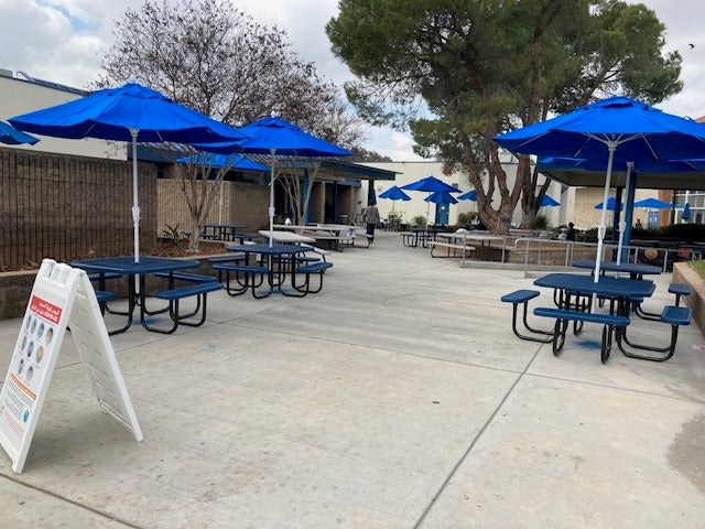 Blue Wabash Valley Signature Square Picnic Tables under blue umbrellas in a school lunch court, picnic tables with separate benches