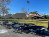 Blue Wabash Valley Signature Square Picnic Tables with Diamond tops and umbrellas beside a school sports field, a square metal picnic table