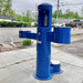 Blue Willoughby Tri-level Drinking Fountain with Bottle Filler and Pet Drinking Fountain on a sidewalk with a road and buildings in the background.