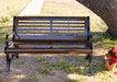 Front Angle of Brown MyTCoat Austin Bench with Horizontal Slatted Steel with Park Background and Colorful Flower Pot