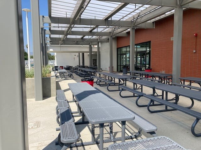 Rows of gray Wabash Valley Signature Portable Picnic Tables under a shade structure in a school lunch courtyard, outdoor school lunch tables