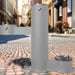 Gray Willoughby Free-standing Double Drinking Fountain Front Access, Child Height, Dog Bowl Options on a cobblestone street with buildings in the background.