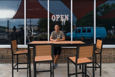 Four Green Valley bar height chairs with Cedar Slats on black frames at a 72 inch bar table outside a bar, outdoor bar stools with backs