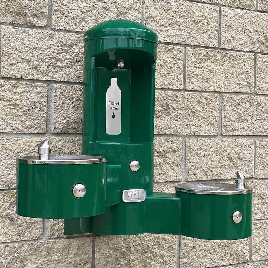 Green Willoughby wall-mounted bottle filler with dual drinking fountains on brick wall