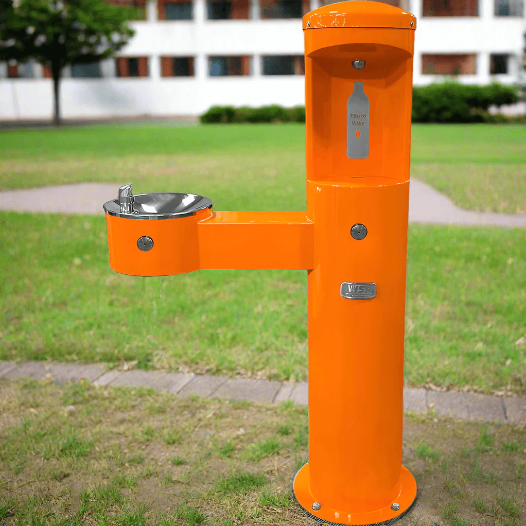 Orange Willoughby Stainless Front Approach Bottle Filler Drinking Fountain with grass and building in the background