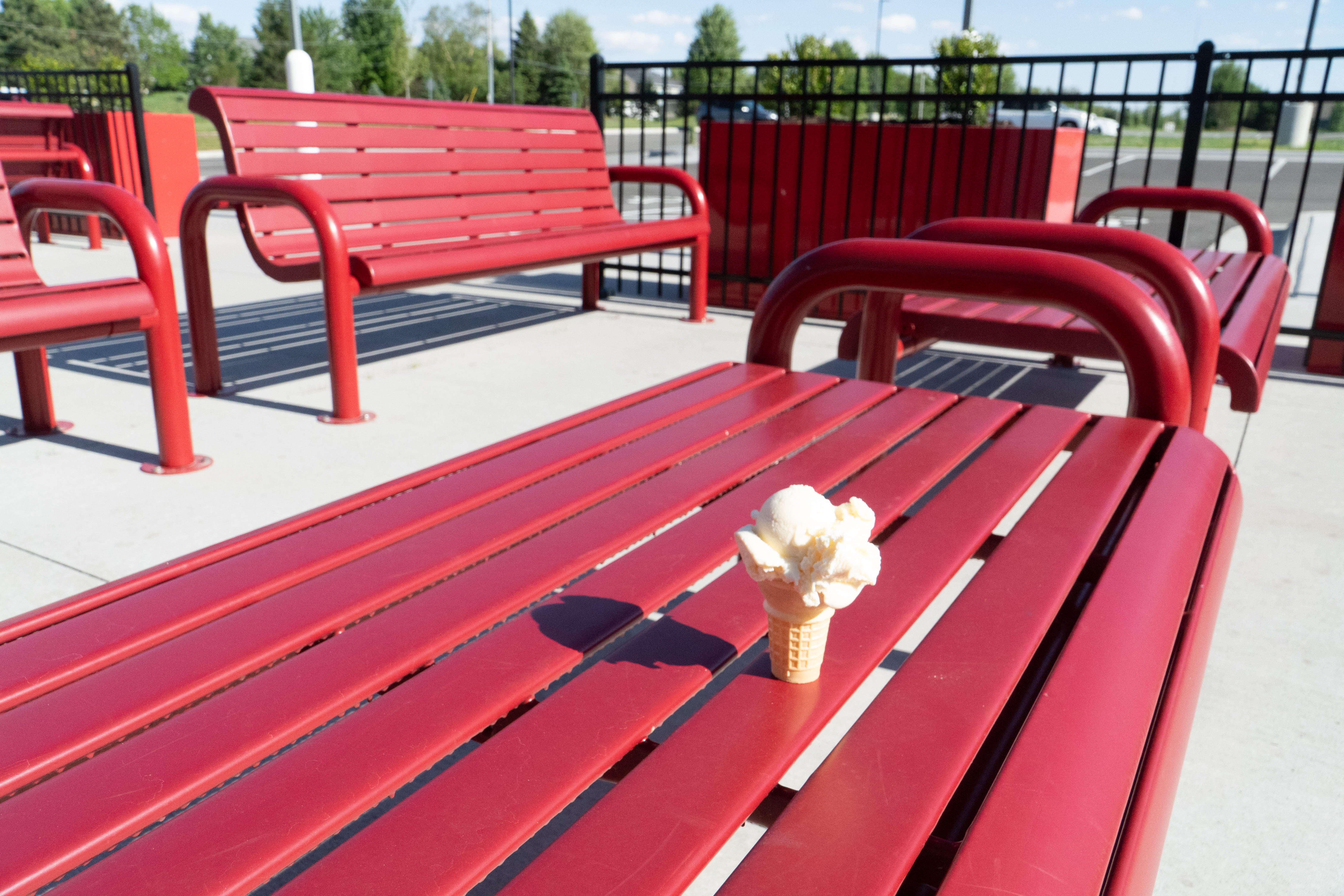 Closeup of Red Wabash Valley Contemporary Slatted Steel Bench Surface Mount showing the powder coated steel bench slat seat and contoured arm