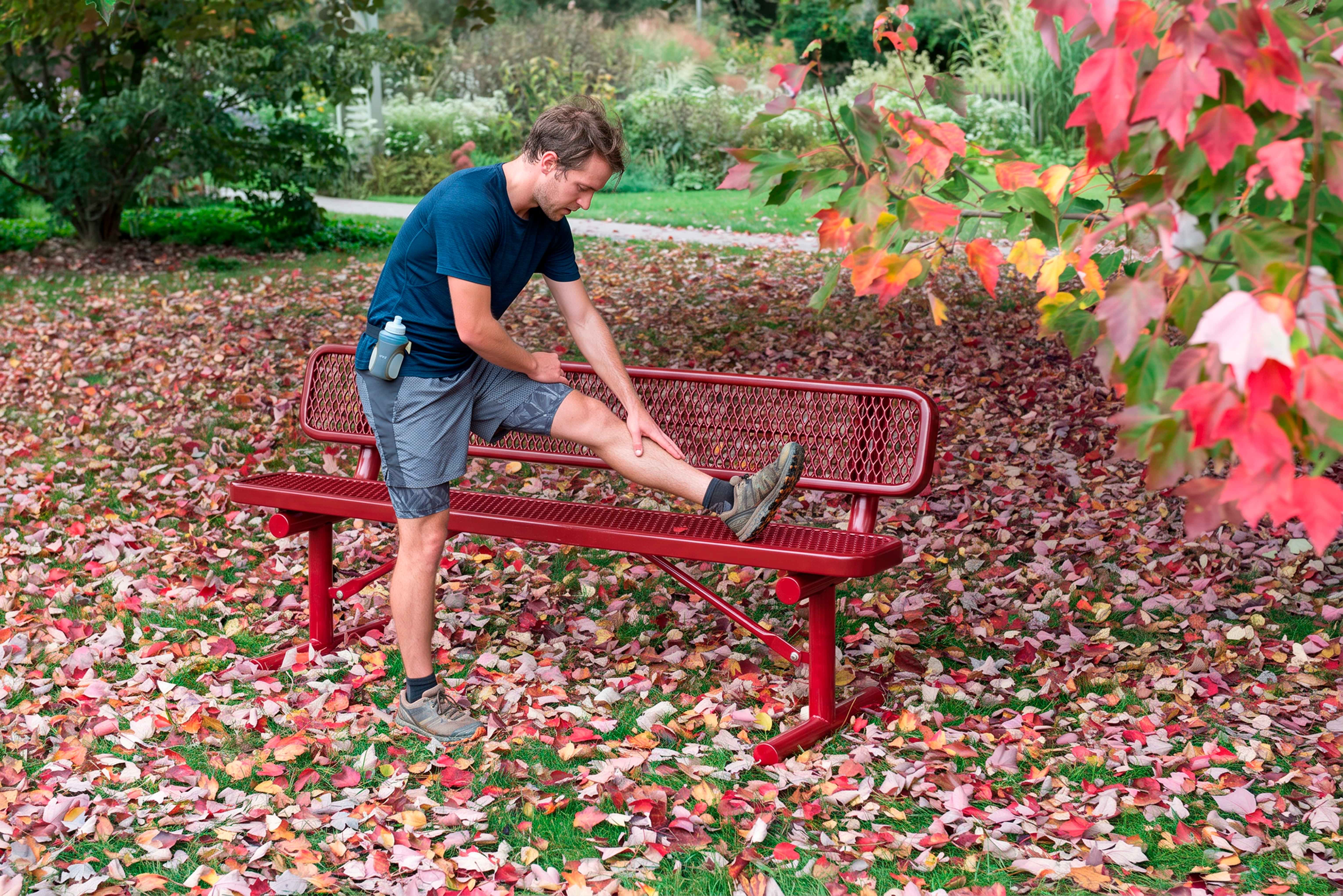 Runner stretching on a Red Wabash Valley Signature Steel Bench, Diamond seat and back, portable frame with braces, metal bench with back