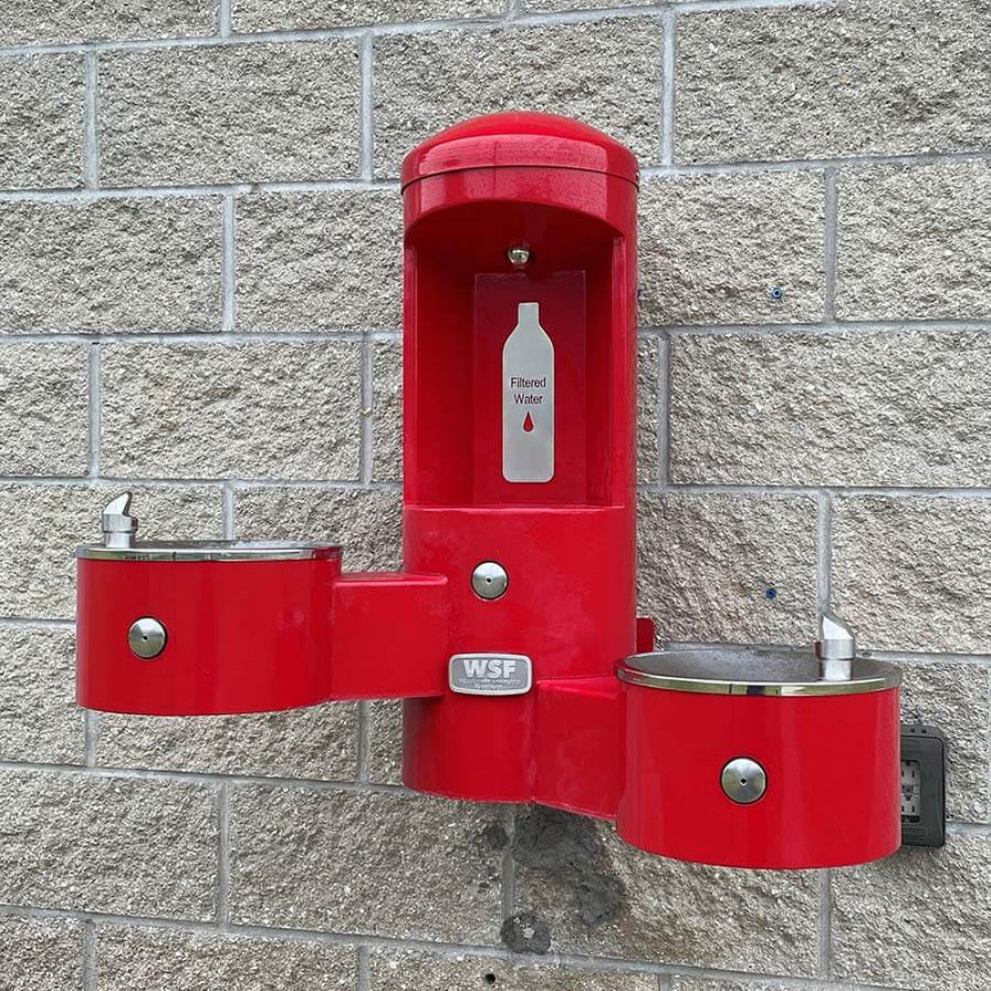 Red Willoughby wall-mounted bottle filler with dual drinking fountains on brick wall