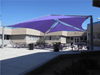 Outdoor seating area with purple USA Shade Super Span Multi-Panel Hip Shade in front of a building