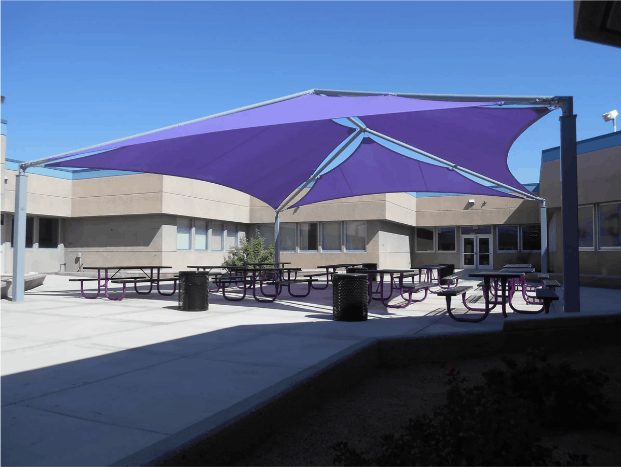Outdoor seating area with purple USA Shade Super Span Multi-Panel Hip Shade in front of a building