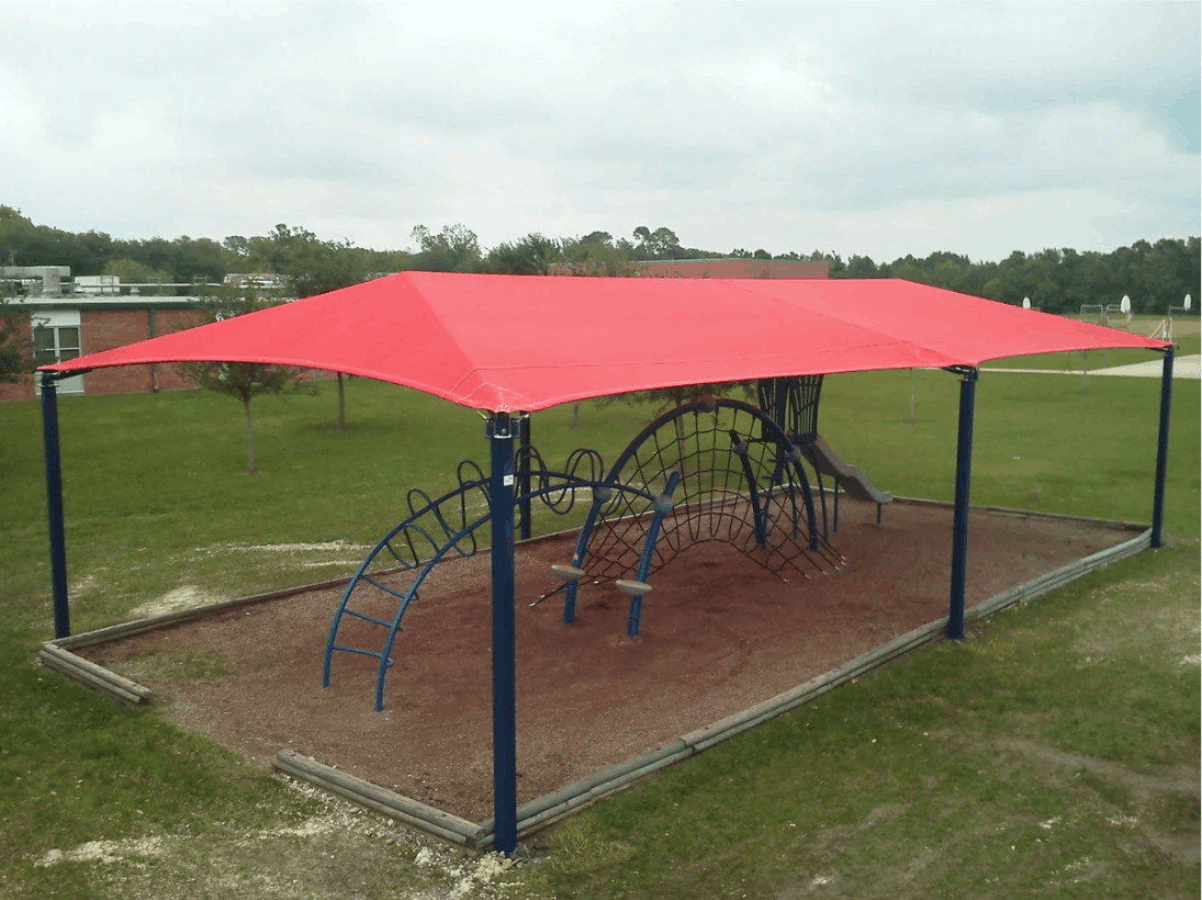 Playground with red USA Shade 6-Post Hip and playground equipment on a grassy area