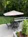 Black Sullivan square steel mesh patio table with four stacking chairs and an umbrella on a backyard deck, patio set for 4