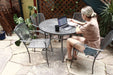 Woman working on a laptop in a silver Sullivan stacking patio chair at a round mesh table, mesh patio chairs