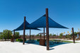 Outdoor shaded area with blue 4-point Hypar sail shades and picnic tables under a clear blue sky.