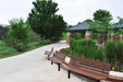 Wabash Valley Fairmount Wood Benches with Thermory ash slats on Inground posts along a park path and flower bed, model FA440N, commercial wood bench