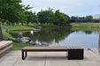 Wabash Valley Liberty Modular Bench with Square Seat facing a park pond, Thermory ash slats on black steel, model LBB002N, outdoor cube seating