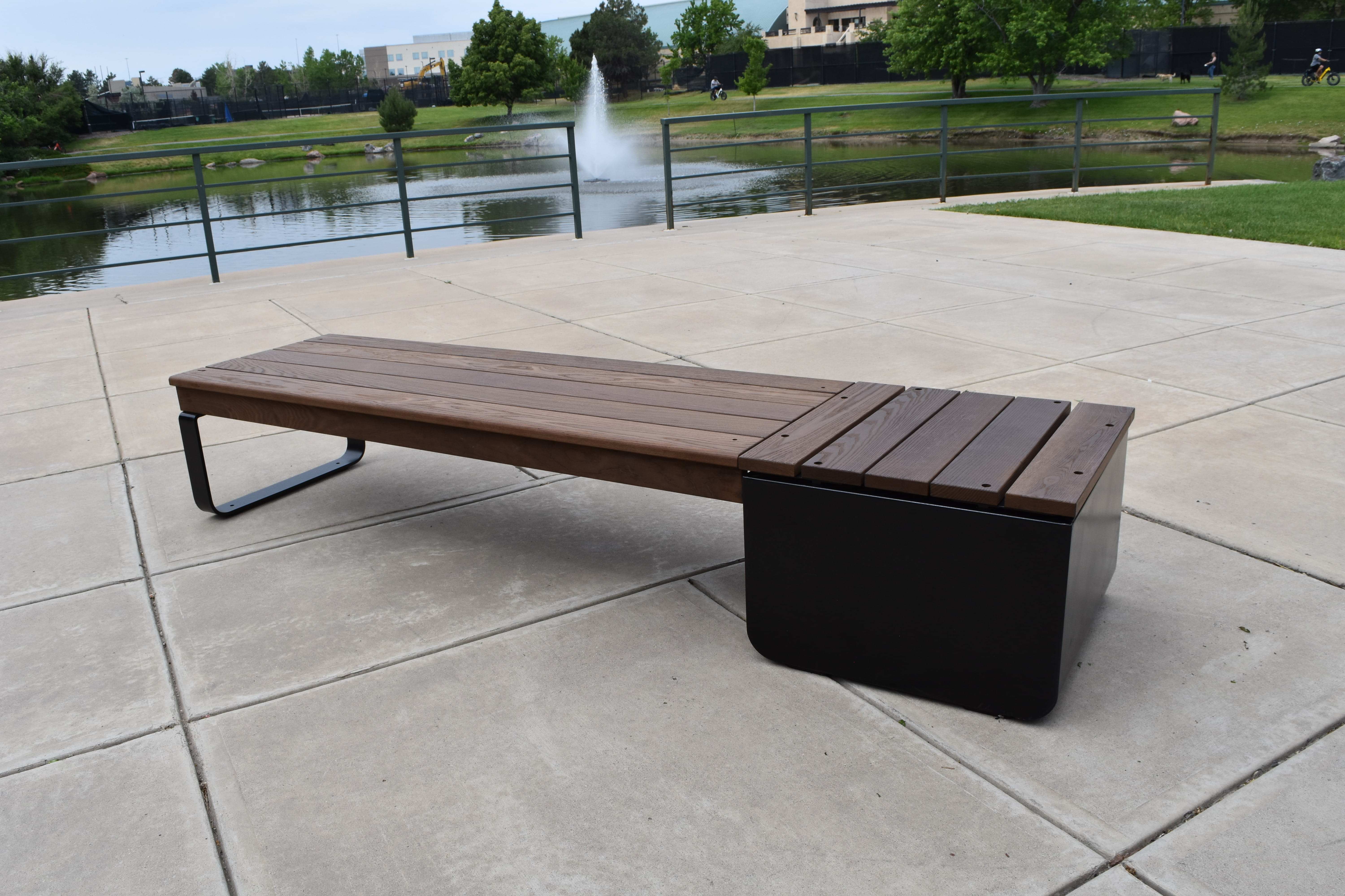 Wabash Valley Liberty Modular Bench with Square Seat on a plaza by a pond and fountain, Thermory ash slats on black steel, model LBB002N, landscape bench