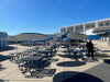 Wabash Valley Signature Square Picnic Tables with umbrellas filling a high school courtyard, 4 sided picnic tables