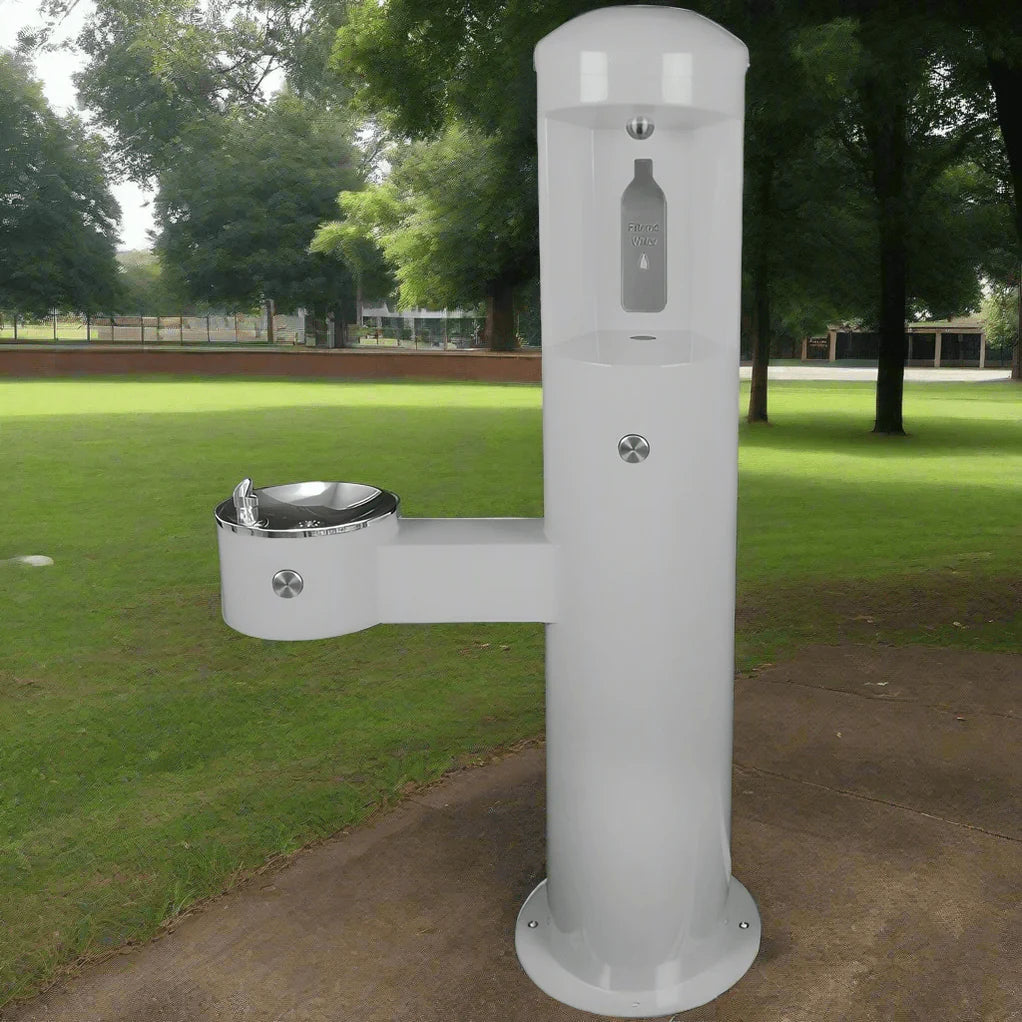 White Willoughby Stainless Front Approach Child Height Bottle Filler Drinking Fountain in a park setting with grass and trees in the background.