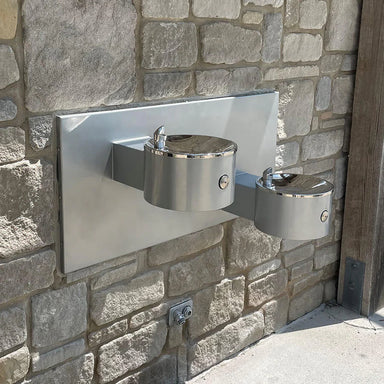Willoughby Double Wall-Mounted Drinking Fountain mounted on a stone wall.
