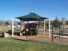 Playground with a green USA Shade Mariner Pyramid Shade and playground equipment on a sunny day.