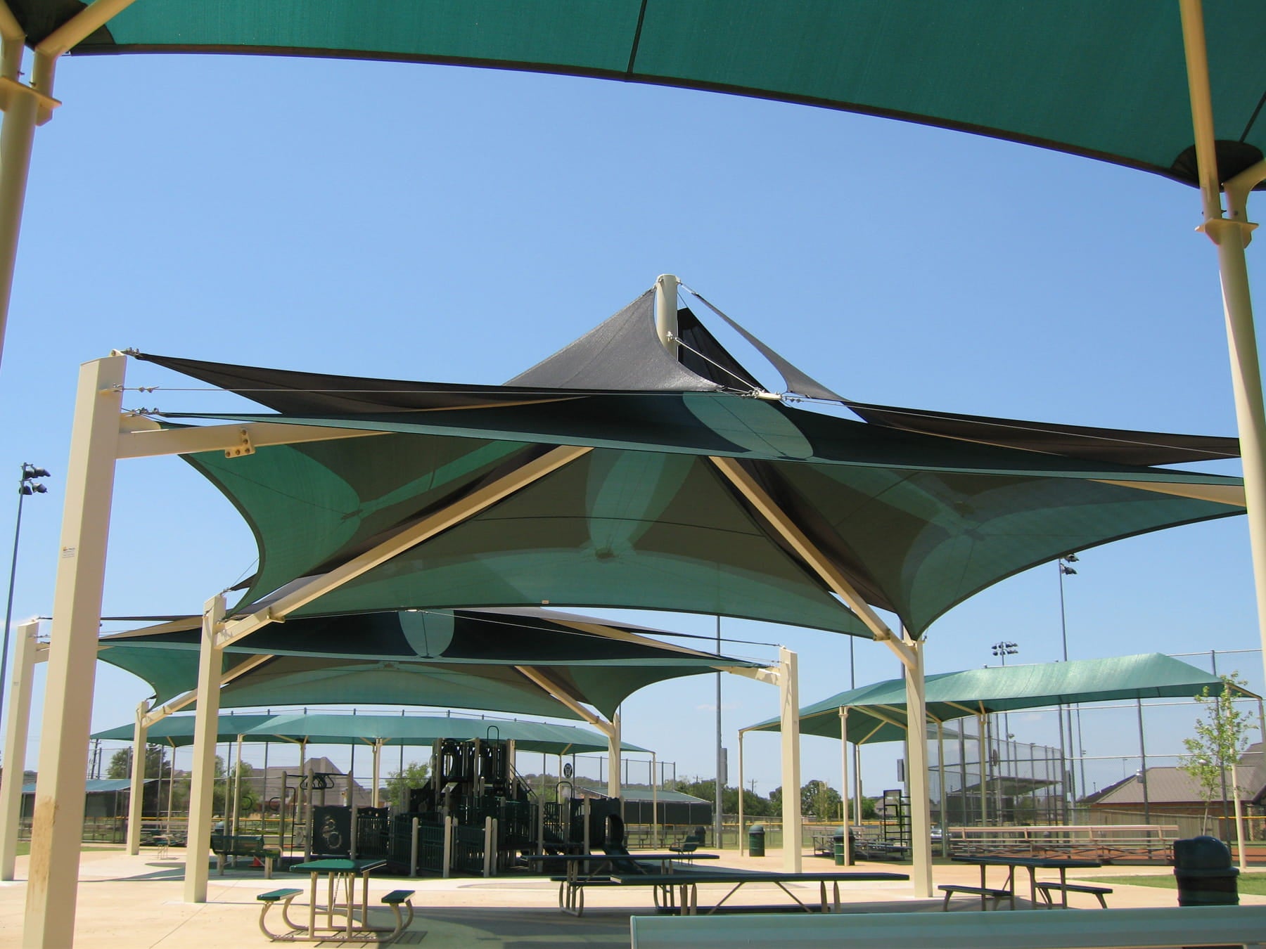 Green USA Shade Multi-Layer Super Span Pyramid Shade structures at a park with clear blue sky