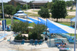 Outdoor pool area with blue USA Shade Wave Shade and lounge chairs on a sunny day.