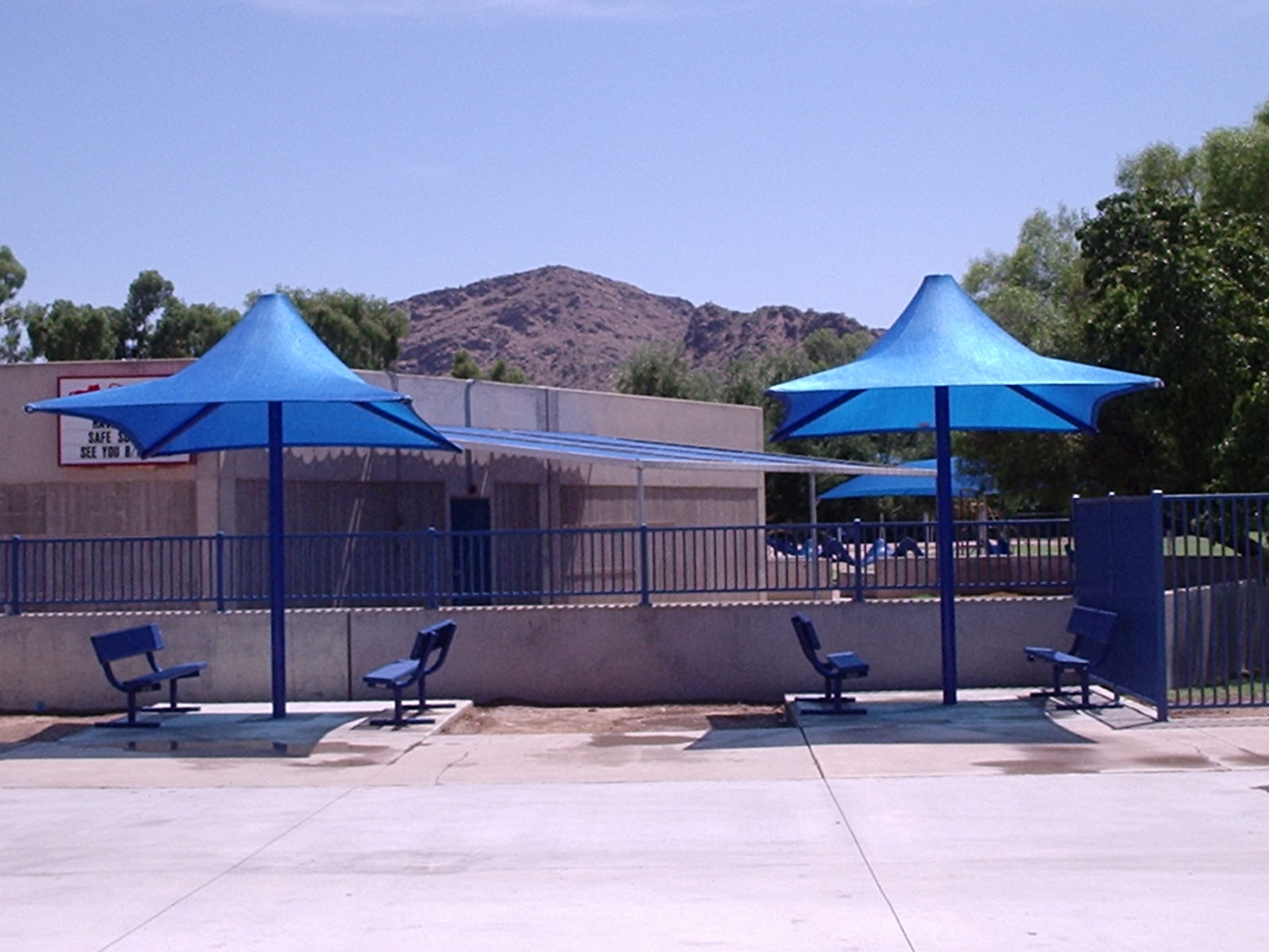 Blue USA Shade Lifeguard Umbrellas and chairs on a concrete surface with mountains in the background