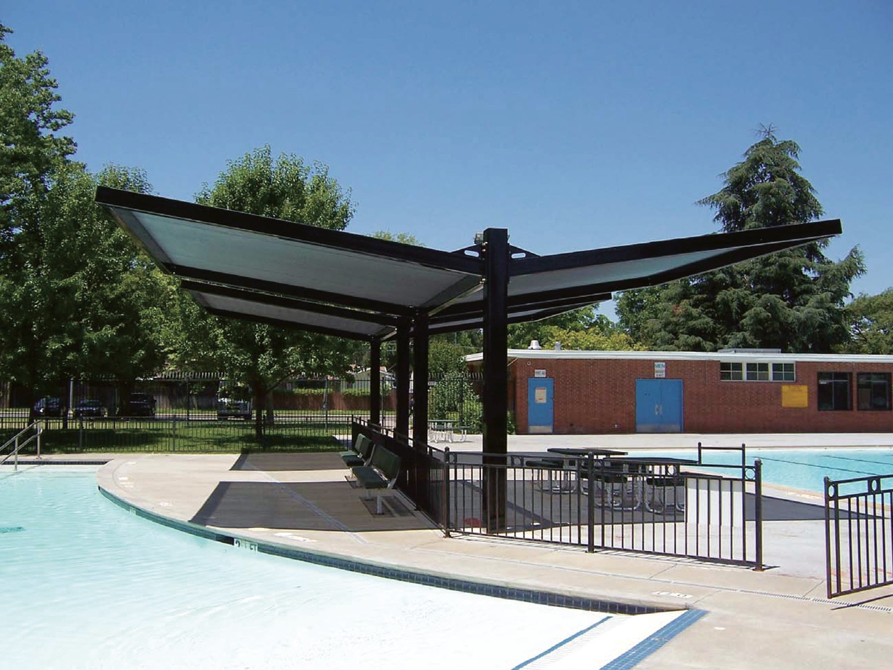 USA Shade Slanted Cantilever Framed double side Unit by a pool with trees and building in the background