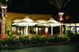 Outdoor restaurant patio with USA Shade 4-point Twilite Umbrellas and palm trees at night