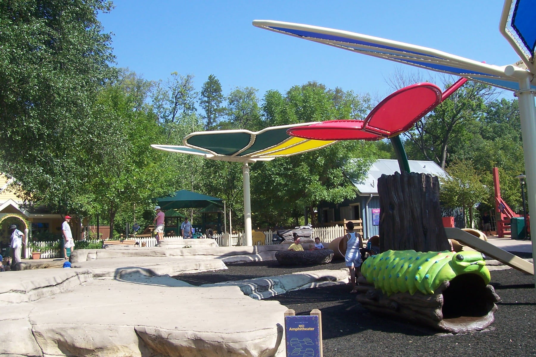 Children's playground with colorful USA Shade Butterfly Wings Shade and people around