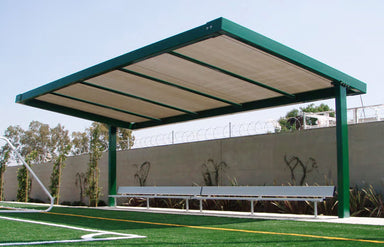 USA Shade Slanted Cantilever Framed Covered seating area with a bench on a sports field