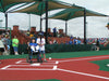Child in a wheelchair at home plate during a baseball game with spectators in the stands. with USA Shade Mariner Pyramid Shade in background