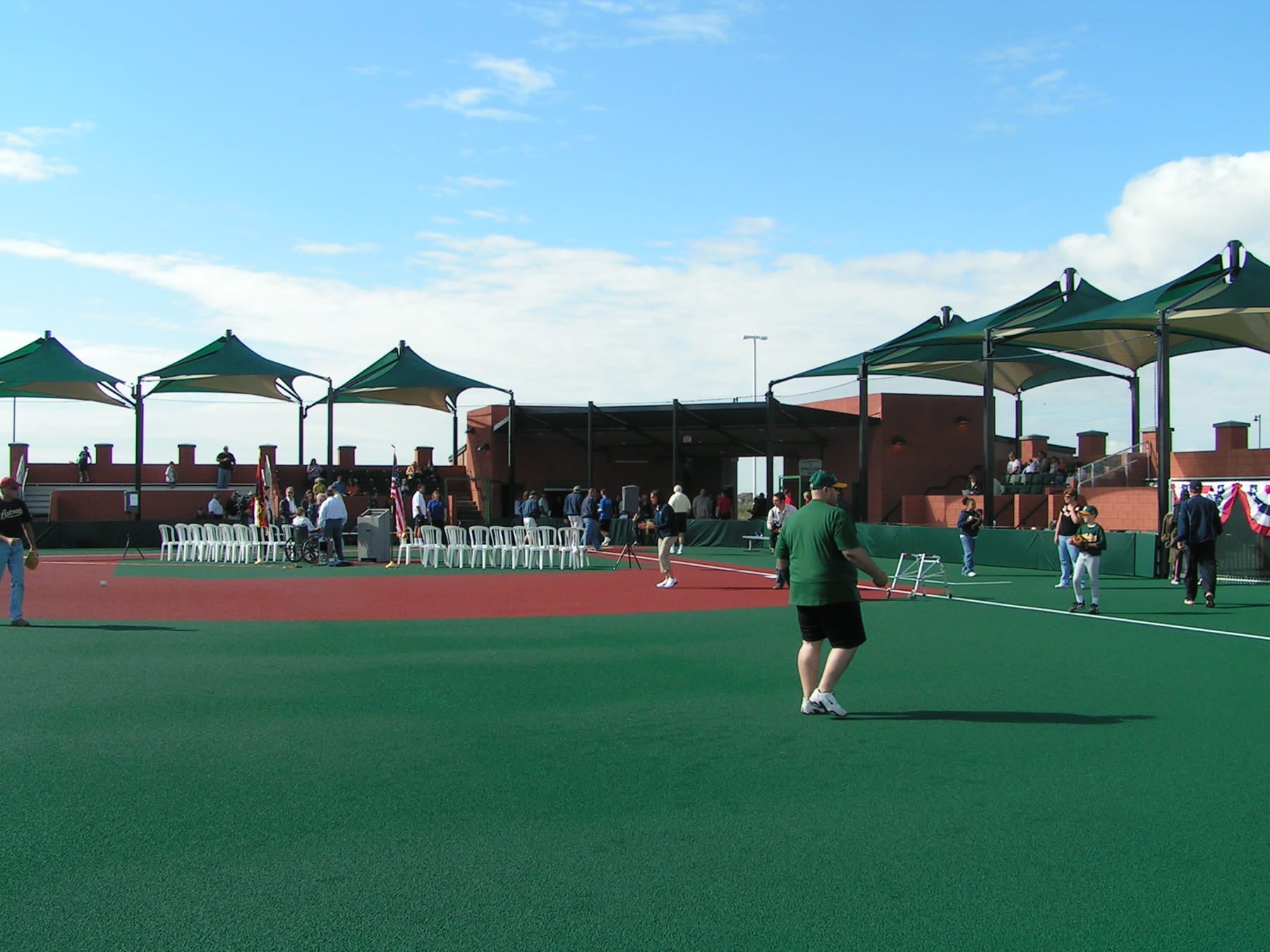 Baseball Field with players and spectators under green USA Shade Mariner Pyramid Shades on a sunny day.