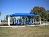 Children's playground with blue USA Shade Hip and slides in a park setting