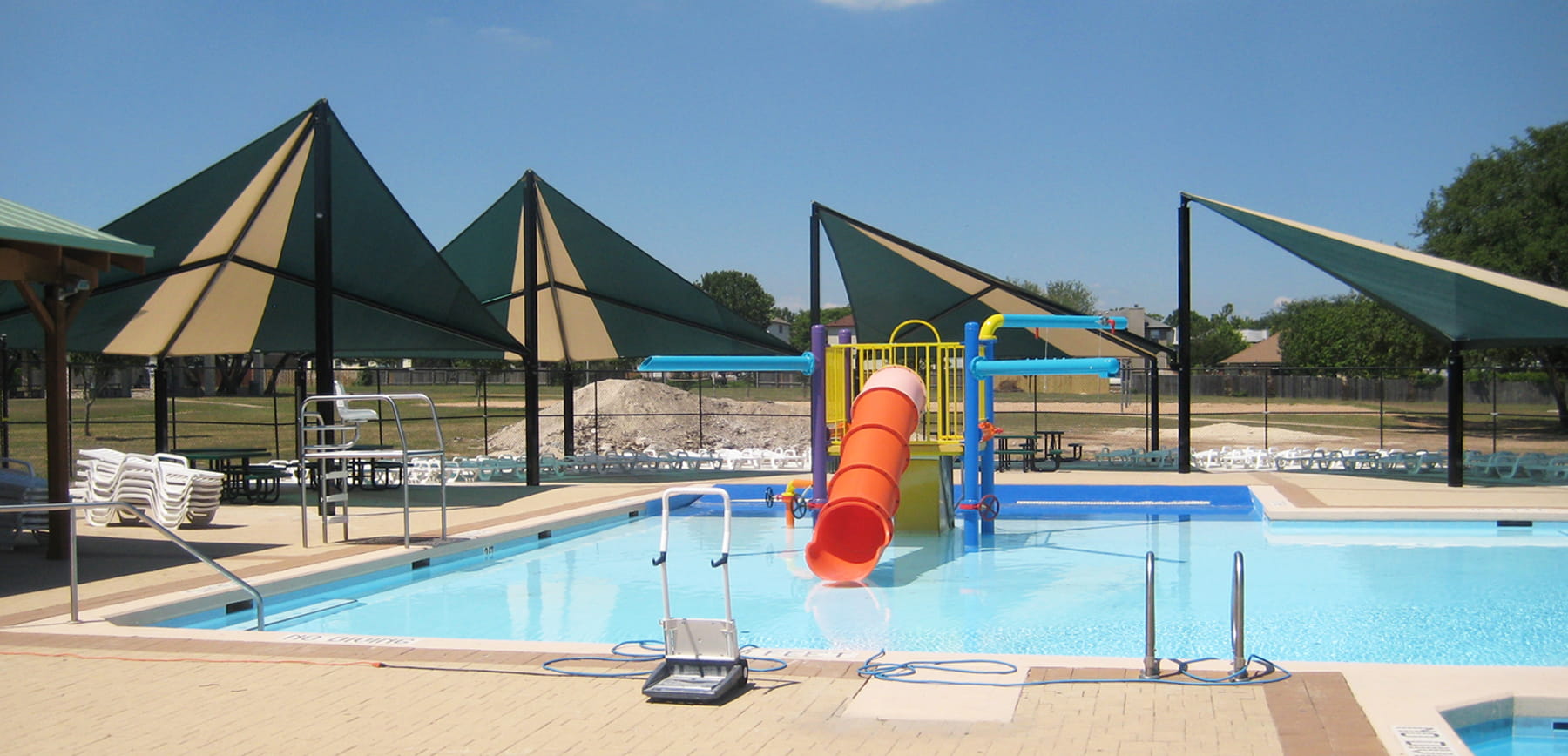 Pool area with slides and USA Shade Wave Shades on a sunny day