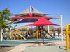 Children's playground with slides and swings under a large red and gray USA Shade Multi-Layer Super Span Pyramid Shade on a clear day.