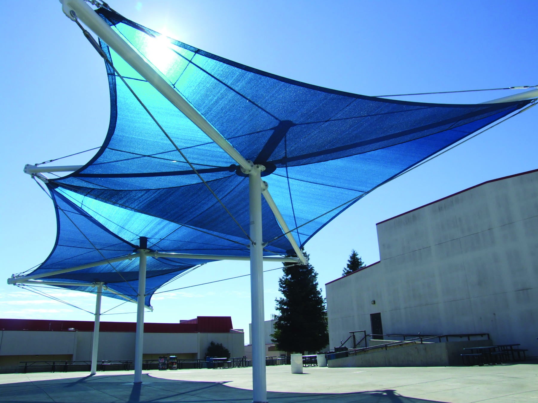 Blue USA Shade Aurora Shade sail structure against a clear blue sky with buildings in the background