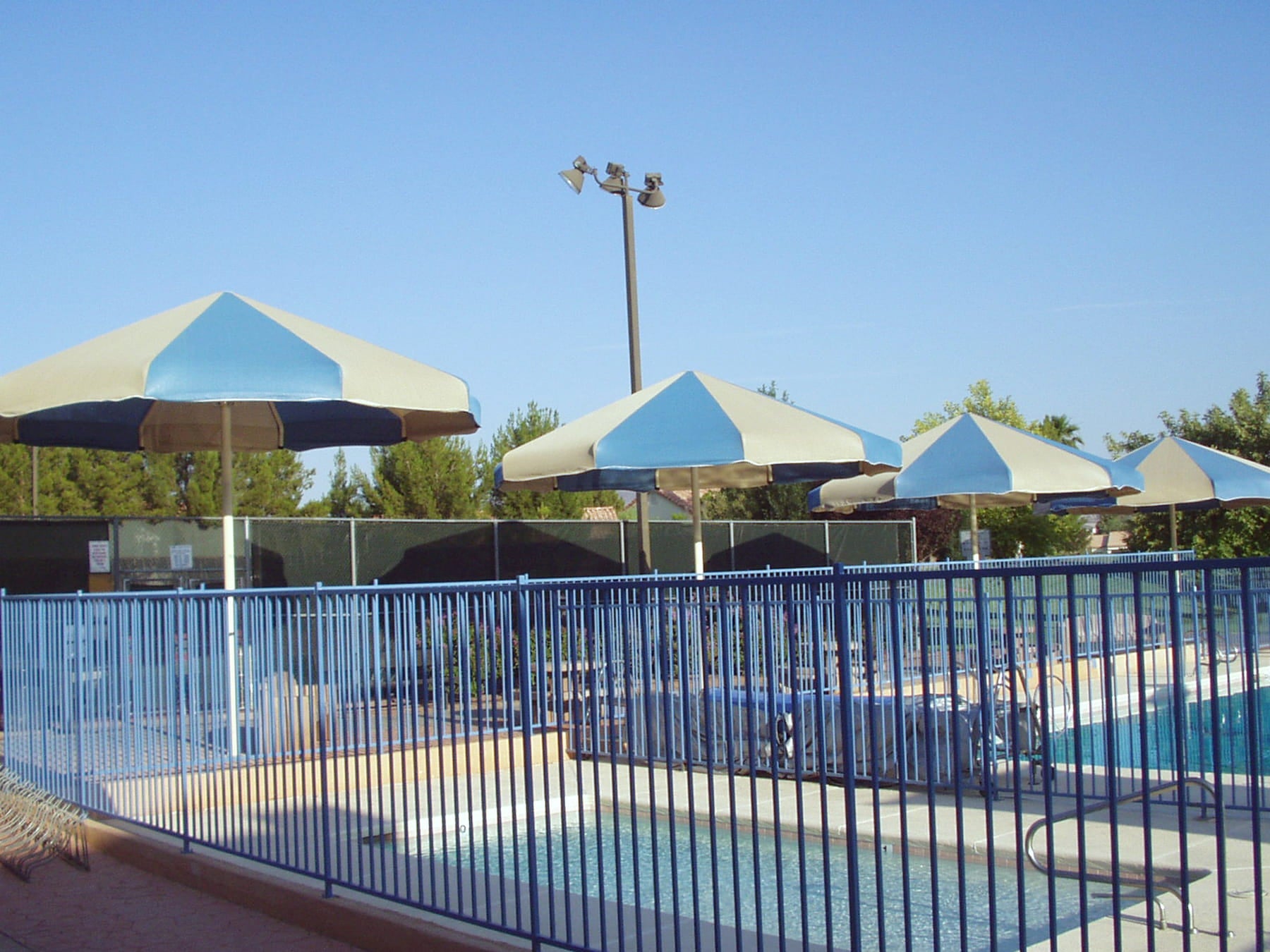 USA Shade Coolbrellas and a pool area with a blue fence under a clear sky.