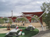 Outdoor picnic area with red USA Shade Pegasus Shade structures and picnic tables in a park setting.