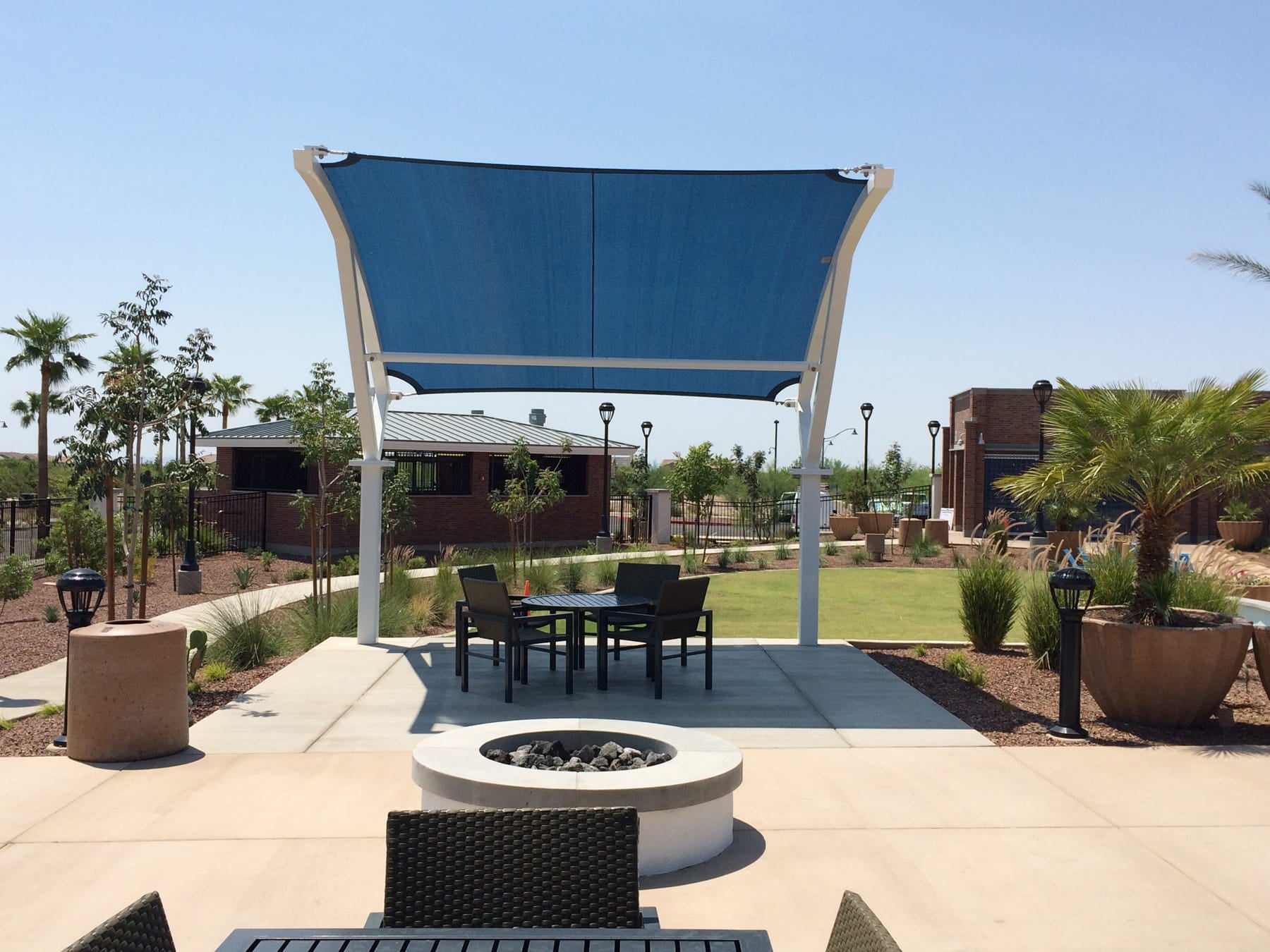 Outdoor patio area with a blue USA Shade Panorama Cantilever, tables, chairs, and a fire pit.