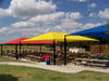 Outdoor seating area with colorful USA Shade Hips and picnic tables under a blue sky.