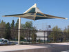 Large geometric USA Shade Solana Cantilever on a pole against a blue sky with trees and buildings in the background.