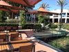 Outdoor seating area with wooden tables and orange USA Shade Solana Cantilevers in a garden setting.