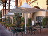 Outdoor seating area with tables, chairs, and USA Shade 4-point Twilite Umbrellas in front of a building with 'S Sushi' sign.