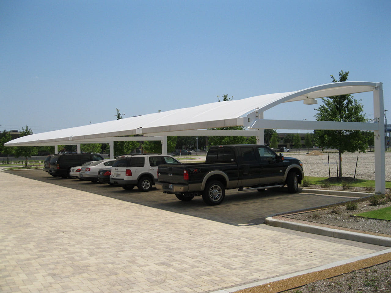 USA Shade Full Arch Cantilever with multiple vehicles parked underneath on a clear day