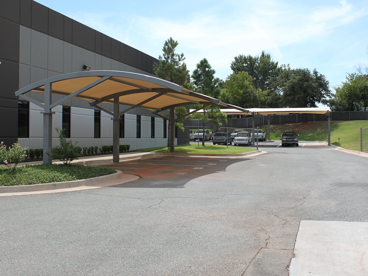 USA Shade Panorama Cantilever Covered parking area in front of a building with trees in the background