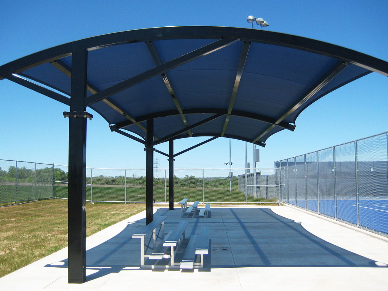 Covered sports facility with blue USA Shade Panorama Cantilever over seating area on a clear day